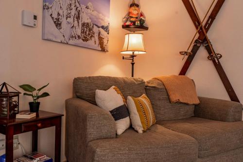 a living room with a brown couch with pillows at Chase's River Cabin - Hot-tub Firepit & Fireplace in Granite Falls