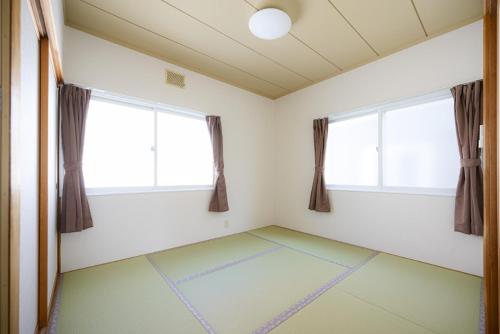 an empty room with two windows and a green floor at ROOMzero 5号室 in Hanazonomachi