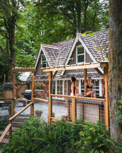 two women sitting on a fence in front of a house at Stilly River Haus - Hot tub - Firepit - Fireplace in Granite Falls