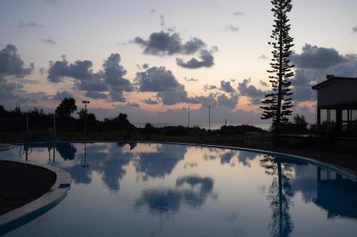 a large swimming pool with a cloudy sky in the background at Coral Palms in Amami