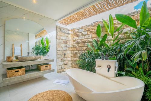 een badkamer met een wit bad en een spiegel bij Sun Garden Villa - 2BR Villa in Kerobokan in Kerobokan