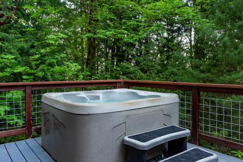 a bath tub sitting on a wooden deck with trees at Bellingham A-Frame - Hot tub - Fireplace - Firepit in Bellingham