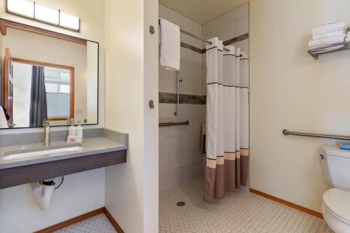 a bathroom with a sink and a toilet and a mirror at Snowcreek Suite - Cedar - ADA- Hot Tub - Kitchenette in Leavenworth