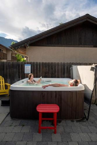 two people in a hot tub with a red stool at Snowcreek Suite - Cedar - ADA- Hot Tub - Kitchenette in Leavenworth
