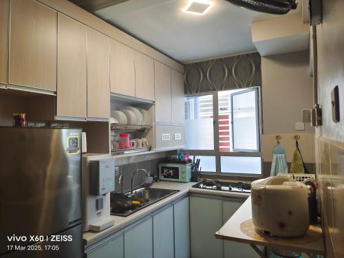 a kitchen with white cabinets and a stainless steel refrigerator at Penginapan Puncak 28 in Kuala Terengganu