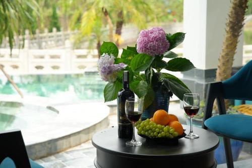 a table with a bottle of wine and a bowl of fruit at Happy Tam Coc Ecolodge in Ninh Binh
