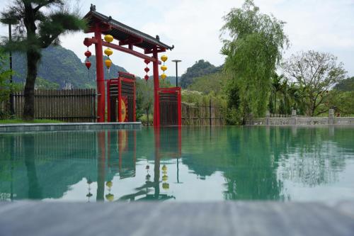 a pool of water with a red structure in it at Happy Tam Coc Ecolodge in Ninh Binh
