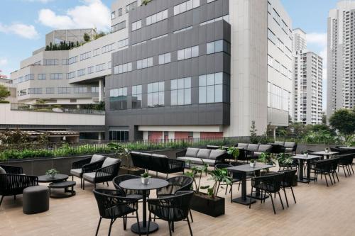 a patio with tables and chairs in front of a building at Quincy House Singapore in Singapore