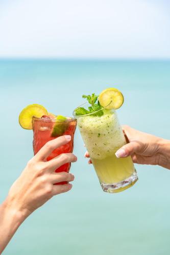 two people holding two cocktails in their hands at Nikki Beach Resort & Spa Koh Samui in Lipa Noi