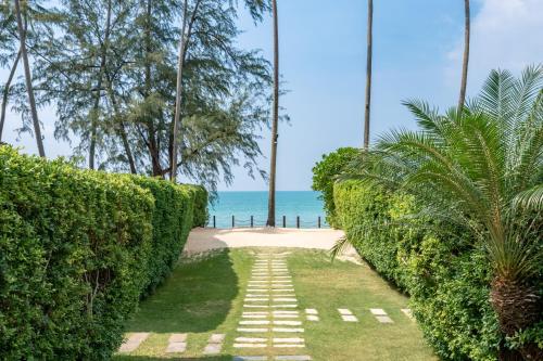 a pathway leading to the beach with trees and the ocean at Nikki Beach Resort & Spa Koh Samui in Lipa Noi
