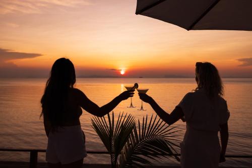 two women holding martini glasses in front of the ocean at Nikki Beach Resort & Spa Koh Samui in Lipa Noi