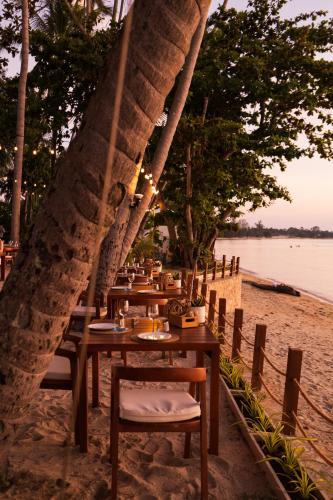 a restaurant on the beach with tables and chairs at Nikki Beach Resort & Spa Koh Samui in Lipa Noi
