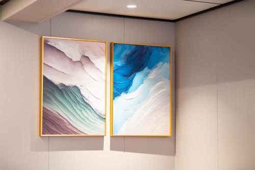 two paintings on a wall in a room at Vientiane Yooeun Hotel in Vientiane