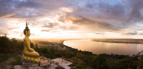 a large gold statue on a hill next to a lake at ANOU HOSTEL in Pakse