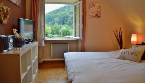 Schlafzimmer mit einem Bett und einem Fenster in der Unterkunft Le Gîte de l'Ecureuil in Sturzelbronn