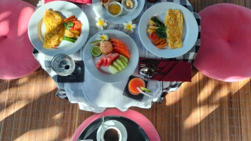 a table with plates of food on top of it at Aura Guesthouse in Ubud