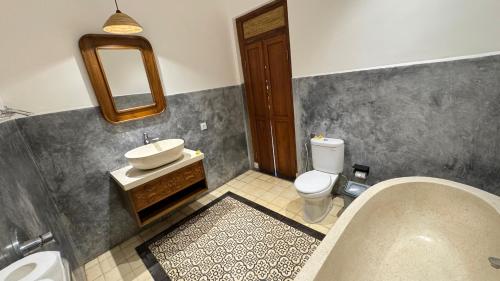 a bathroom with a tub and a sink and a toilet at Villa Karma Loka in Sidemen