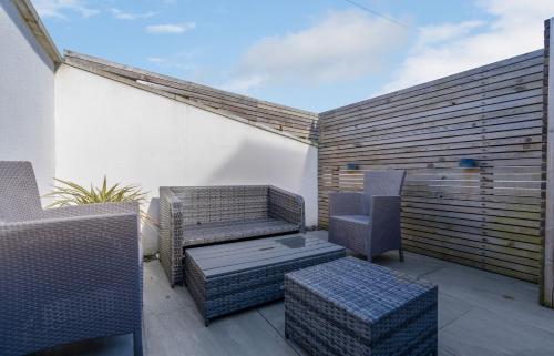 a patio with wicker chairs and tables on a balcony at The Kepties 4 - Luxurious Serviced Apartment by ORION SHORT STAYS in Arbroath