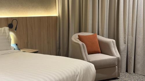 a bedroom with a bed and a chair with a pillow at فندق آرام النسيم in Ash Shishah