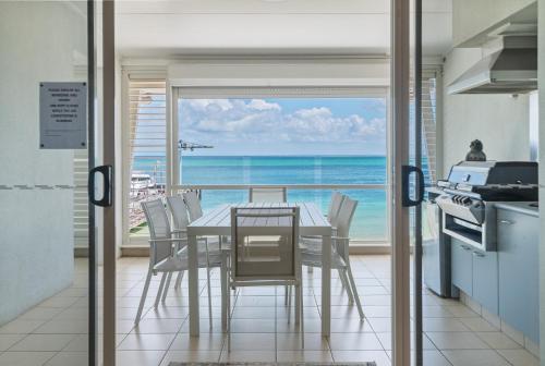 a dining room with a table and a view of the ocean at Deep Blue Apartment 8 in Tangalooma