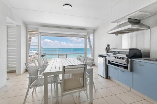 a kitchen with a table and a view of the ocean at Deep Blue Apartment 8 in Tangalooma