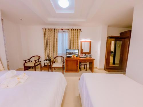 a bedroom with two beds and a desk and a mirror at Lanxy Hotel Nha Trang in Nha Trang