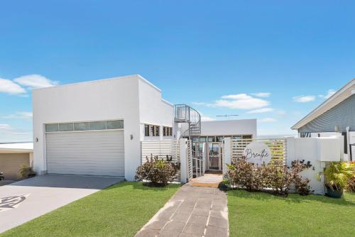 a white house with a garage at Breathe On Moreton will take your breath away in Tangalooma