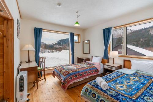 a bedroom with two beds and a desk and a window at Anaba Lodge in Kitaakita