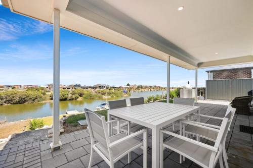 a table and chairs on a patio with a view of a river at 29 Blanche Pd, Hindmarsh Island in Hindmarsh Island