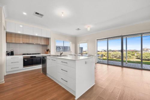 an empty kitchen with white cabinets and windows at 29 Blanche Pd, Hindmarsh Island in Hindmarsh Island