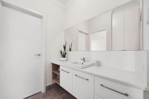 a white bathroom with a sink and a mirror at 29 Blanche Pd, Hindmarsh Island in Hindmarsh Island