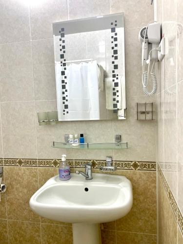 a bathroom with a sink and a mirror and a phone at Asson Hotel Termez in Termiz