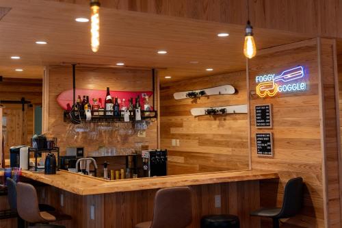 a bar in a restaurant with wooden walls and chairs at Anaba Lodge in Kitaakita