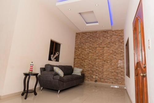 a living room with a couch and a brick wall at Casa Moderna in Acajutla