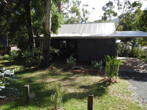 a small house with a tree in the yard at Halls Gap Cottages in Halls Gap