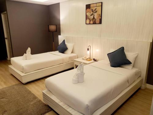 a room with two beds and a table with a lamp at Curve Boutique Hotel in Pattaya