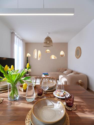 - un salon avec une table en bois et des verres dans l'établissement 2BR Apartment near Colmar Centre - Boho Style, Hidden Room, Free Parking, à Colmar