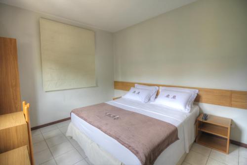 1 dormitorio con 1 cama blanca grande con almohadas blancas en Hotel Pedra da Concha, en Salvador