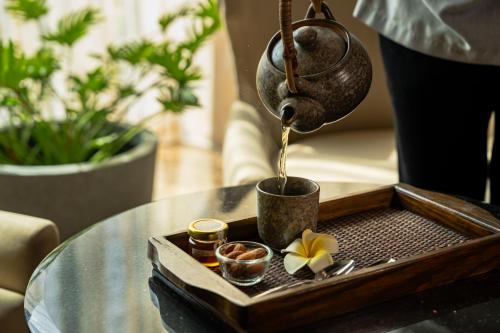 a tea pot being poured into a tray on a table at Sheraton Grand Bangalore Hotel at Brigade Gateway in Bengaluru