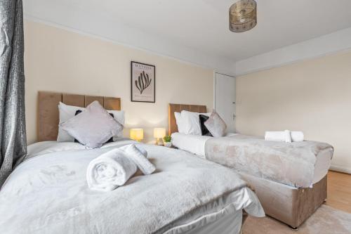 two beds in a bedroom with white sheets at Cosy 2 bed flat, Wembley Stadium in London