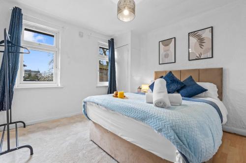 a bedroom with a large bed with blue pillows at Cosy 2 bed flat, Wembley Stadium in London