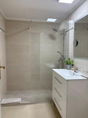 Un baño con ducha, lavabo y espejo. en Bonito Apartamento en Frente del Mar, en Jávea