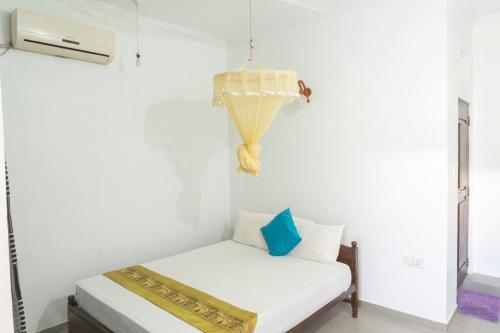 a white room with a couch and a chandelier at Blumarine Guest House in Negombo
