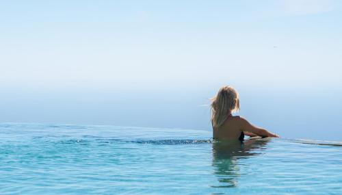 a woman sitting on a surfboard in the water at MATHIS Lodge Amed in Amed
