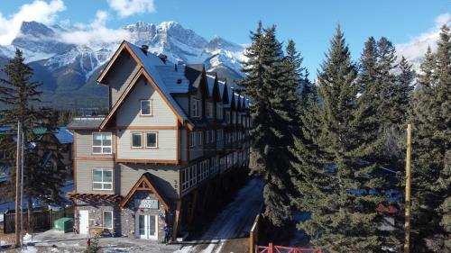 ein großes Haus mit schneebedeckten Bergen im Hintergrund in der Unterkunft Memory Lodge in Canmore