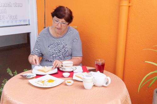 a woman sitting at a table with a plate of food at Blumarine Guest House in Negombo