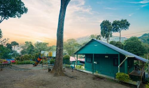 a blue building with a tree in front of it at Hill Valley Farm House in Nelliyampathy