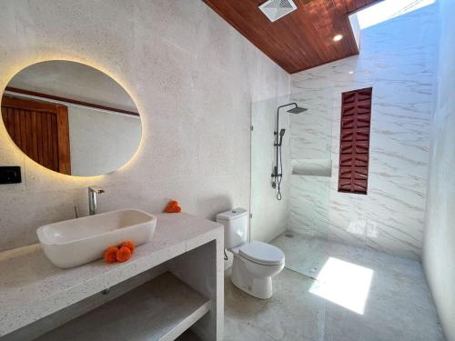 a bathroom with a sink and a toilet and a mirror at Kelapa Villa Mambal 2 in Mambat