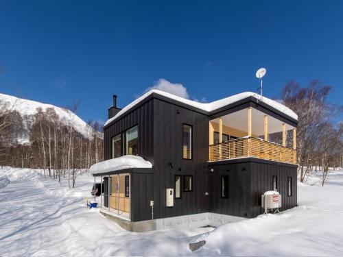 a black house in the snow in the snow at Tanuki House with spacious living room close to Rusutsu Resort in Rusutsu