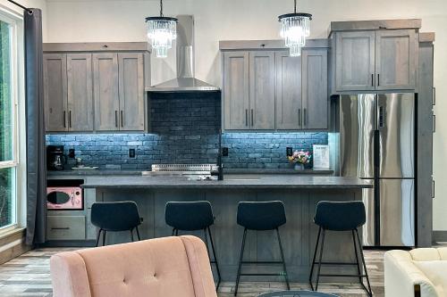a kitchen with wooden cabinets and a bar with stools at New Cougar Cabin with Air Hockey in Purcell